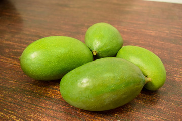 Organic Young Green Mangoes on Wooden Table sour fruits.
