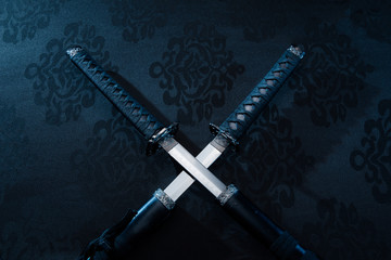 Two katanas with partially drawn blades on fabric