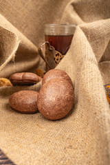 A faceted glass of tea in a vintage Cup holder and chocolate gingerbread on a background of rough homespun fabric. Close up.