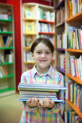 girl with books between shelves in library.