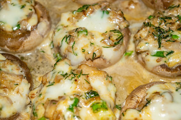 mushrooms baked in the oven with cheese, onion and dill. Close up.