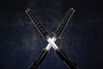 Two crossed katanas with partially drawn blades