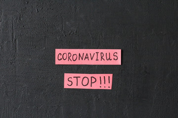 The word Coronavirus stop is written on a red piece of paper, on a black modern background....