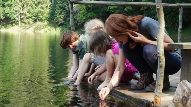 children sitting on a lake shore with their feet in the water
