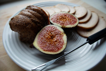 On a white plate meat roll with chopped ripe figs. The roll is cut into round pieces