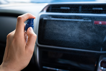 Man is spraying alcohol,disinfectant spray in car for prevention coronavirus disease (covid-19) contamination of germs and wipe clean surface, health care concept (select focus)