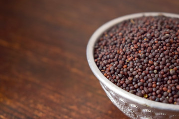 Mustard seeds in a Silver bowl on wooden old Table. Rustic Style