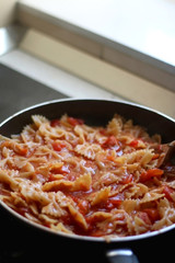 Pasta farfalle with tomato sauce in a pan. Selective focus.