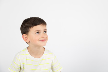 happy little boy looks sideways on white background