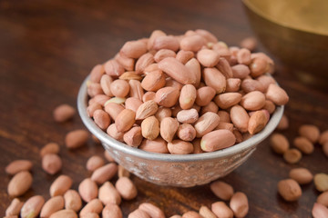 Peeled peanuts in a Silver bowl on wooden old Table. rustic style 