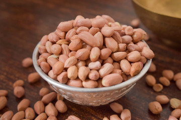 Peeled peanuts in a Silver bowl on wooden old Table. rustic style 