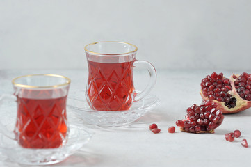 Traditional hibiscus tea made from Sudanese rose petals.  Pomegranate grains complement the composition of two cups with a drink.  Light background.  Close-up.