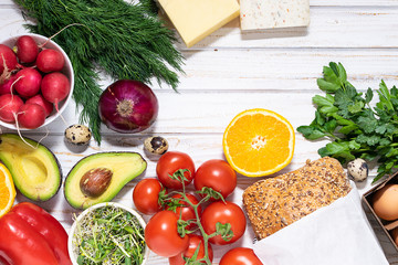 Food delivery concept with assortment of fruit, vegetables, full grain bread, eggs and greens on white rustic background with copy space for your design.