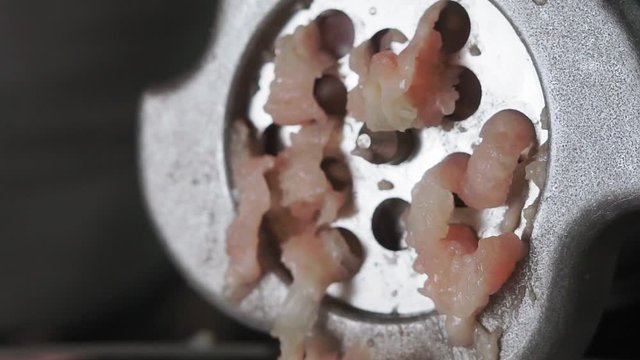 Process of meat grinding in the kitchen with mincing machine. Preparation raw meat for cooking.