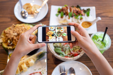woman using a mobile camera take pictures of food placed on the table in house. After calling to order food online from home. Stay at home and shopping online during the spread of the covid-19 virus.