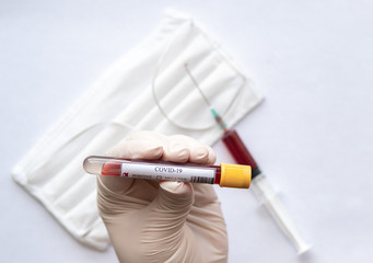 close-up of a positive covid-19 blood test on hand with surgical mask and syringe background.