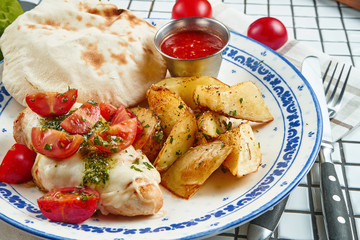Healthy food for lunch: baked potato with chicken fillet with mozzarella and cherry tomatoes on a ceramic plate on a white background. Close up view
