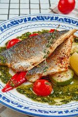 Close up view on fresh pan-fried seabass served with potato and tomato cherry in white plate. Food photo for menu or recipe. Selective focus. Healthy seafood for lunch sea bass