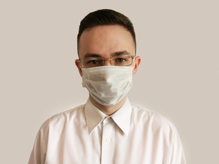 Portrait of a man in a disposable mask and glasses on a gray background. Medical worker in a mask and glasses. Isolation 2020. 2020 virus protection.