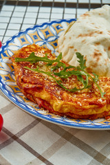 Baked omelet with parmesan and arugula with focaccio bun on an unusual ceramic plate in a composition with ingredients Close up view.