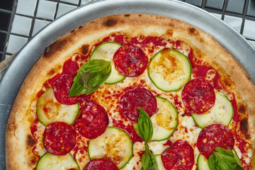 Tasty pizza with salami, zucchini and basil on a white background. Italian traditional cuisine. Delicious food flat lay. Top view