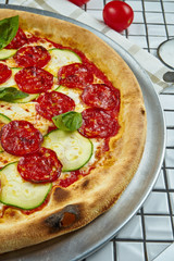 Tasty pizza with salami, zucchini and basil on a white background. Italian traditional cuisine. Delicious food flat lay. Top view