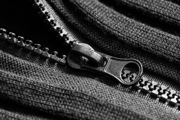 Black  plastic zipper on black knitted fabric. Close up. Macro.