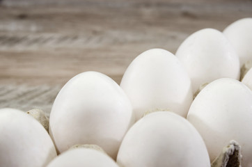 white chicken eggs in a tray on a wooden table.