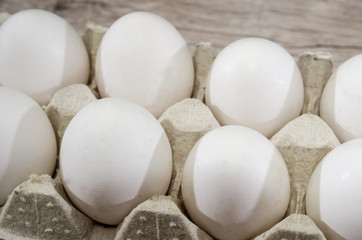 white chicken eggs in a tray on a wooden table.