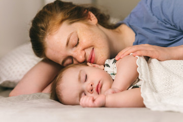 Obraz na płótnie Canvas A nine-month-old baby sleeping in bed with his mother. The benefits of co-sleep with parents for the family