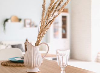 light interior with a vase a jug on a table with dried grass stalks