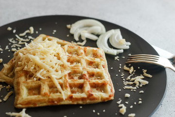 Tasty waffles with zucchini and cheese. Waffles served with cheese, onions, sour cream and spices. Waffles on a plate