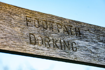 Public Footpath Dorking sign on old weathered wood, a picturesque rural area of Surrey , South east England UK