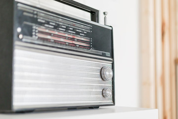 an old Soviet radio receiver from Russia in black with a silver grille on a white shelf