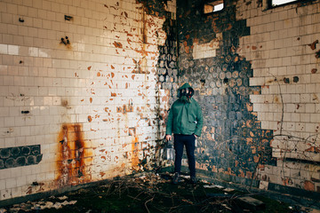 Dramatic portrait of a man wearing a gas mask in a ruined building.