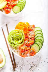 Salmon poke with avocado, cucumber, and rice on marble background , top view. Asian trendy food