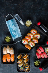Quarantine food delivery. Set of traditional japanese food on a dark background. Sushi rolls, nigiri, raw salmon steak, rice, cream cheese, avocado, pickled ginger. Asian food frame.