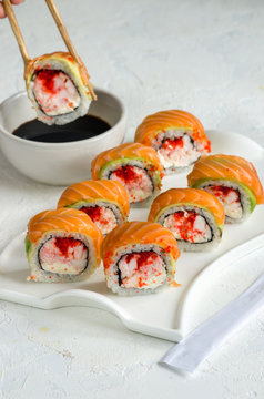 Salmon sushi set on a white plate. Sushi roll with red fish, salmon, red caviar. Roll with fresh salmon, soft avocado, with shrimp and crab and cream cheese under a wide layer of massago caviar.