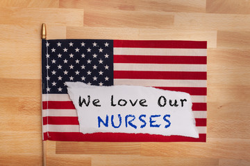 Fototapeta na wymiar Nurse appreciation sign we love our nurses laying on top of an American flag 