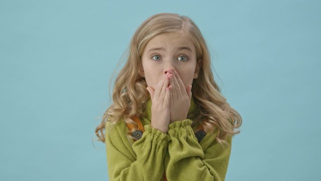 Portrait of a surprised cute girl who becoming scared isolated over blue background