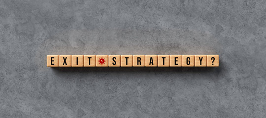 wooden cubes with the word EXIT STRATEGY on concrete background