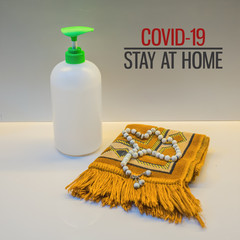 Coronavirus hand sanitizer gel for hand hygiene corona virus protection and a prayer mat or sejadah with text "COVID-19 STAY AT HOME"