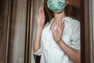 Woman wearing mask protection at the window wait for epidemic situation to improve soon at home....