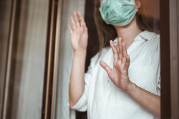 Woman wearing mask protection at the window wait for epidemic situation to improve soon at home. Coronavirus, covid-19, Work from home (WFH), Social distancing, Quarantine, Prevent infection concept.