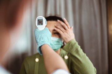 Doctor check patient body temperature using infrared forehead thermometer at hospital for Corona...