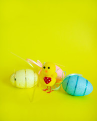 A small toy chicken with three Easter eggs