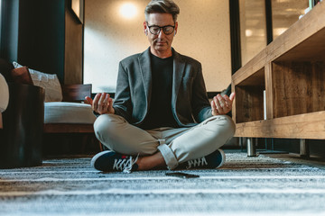 Businessman doing relaxation yoga in office lounge