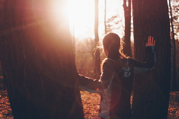 Beautiful scene of a young woman standing between two trees watching sunset 