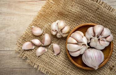 A heap of white garlic cloves and bulb peeled on vintage sack and brown table, a good vegetable for health and medicine, top view image