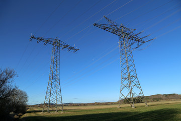Landscape with electric pylons against the blue sky